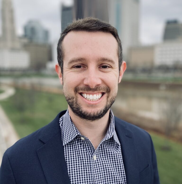 Brett Rosenstein smiling at the camera in front of the Chicago city skyline.